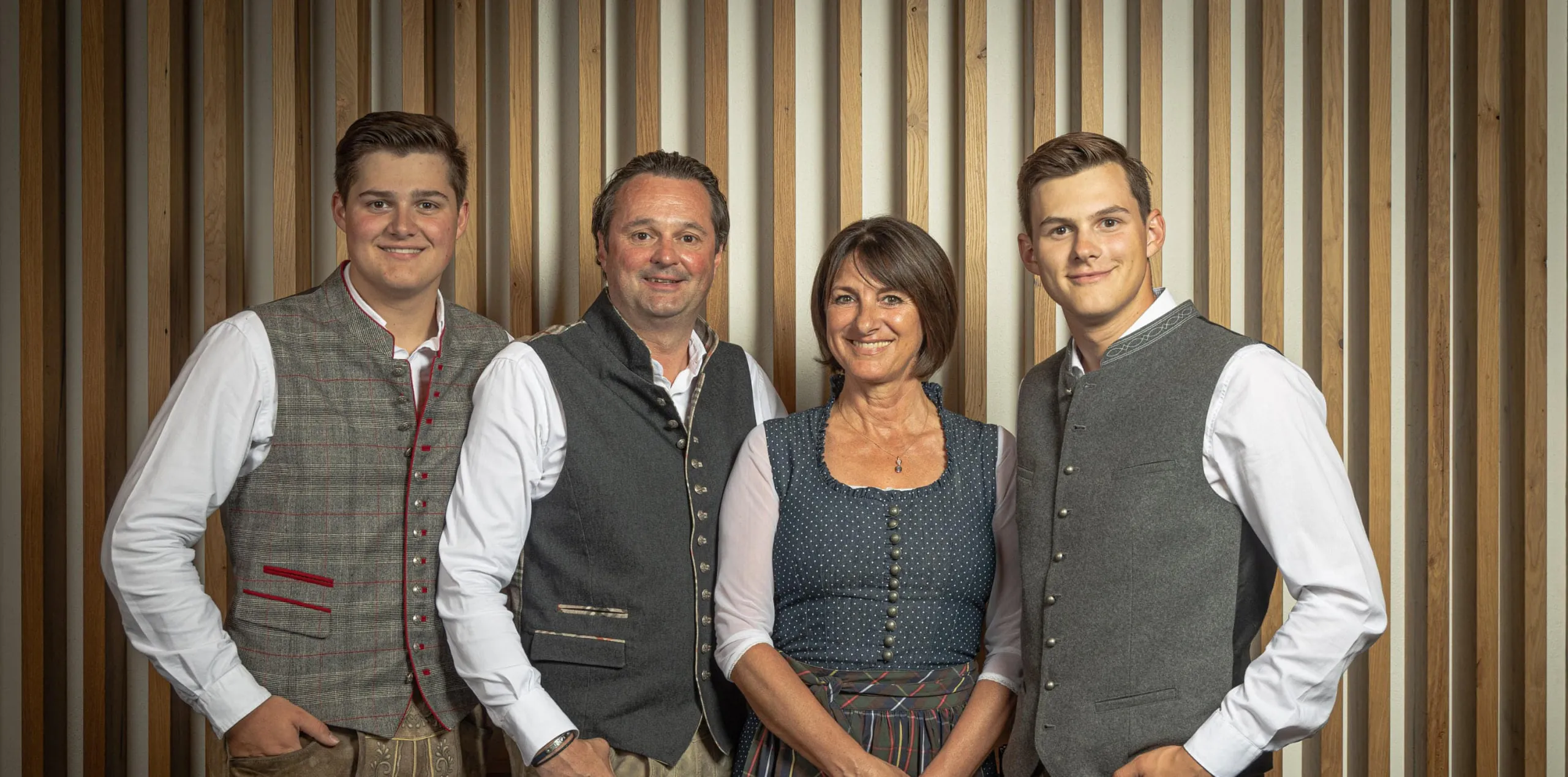 Gruppe von vier Personen vor einem Holz-Hintergrund
