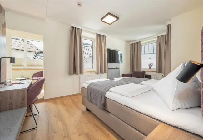 Helles Hotelzimmer mit zwei Fenstern und modernem Mobiliar