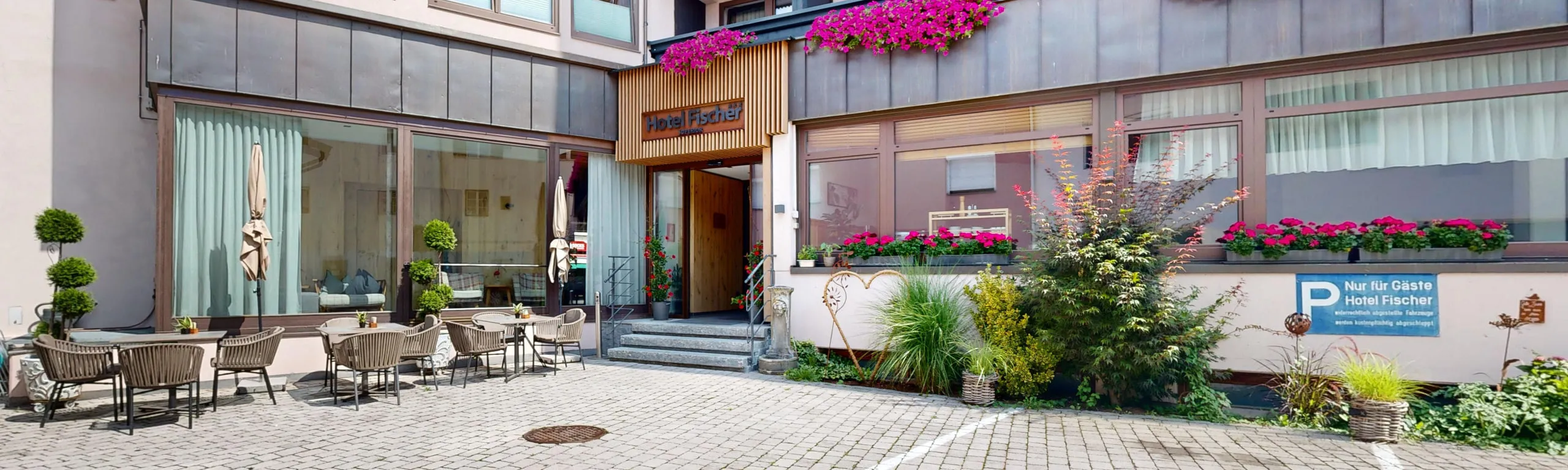 Innenhof und Eingangsbereich des Hotel Fischer mit Blumenbalkonen im Sommer